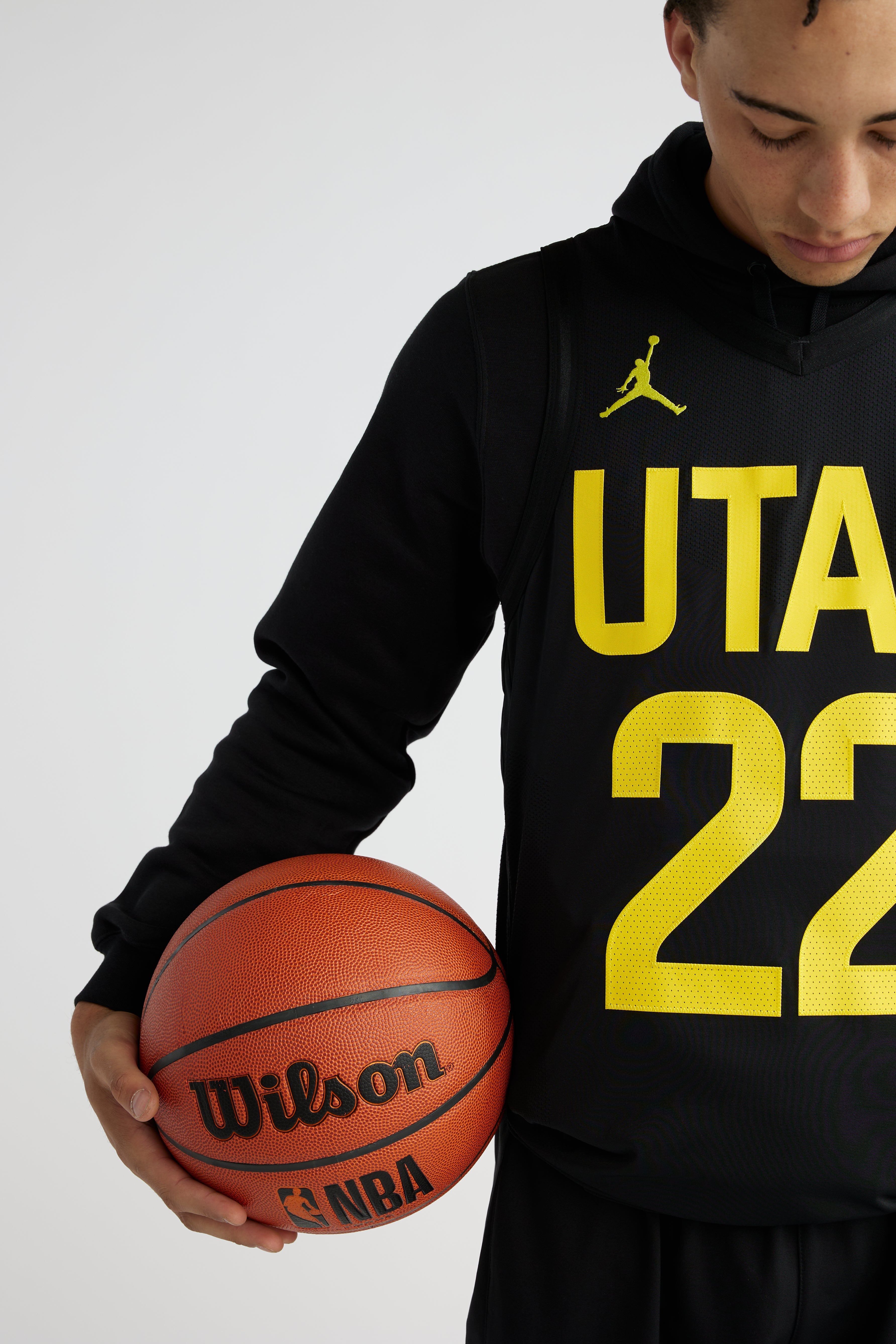 A man wearing the black Jordan jersey featuring the Jordan Jumpman logo on the upper right collar and the UTAH 22 in yellow.